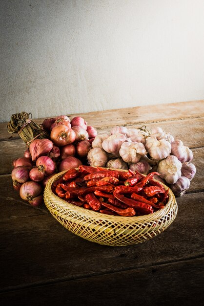 Oignons, ail et piment sec sur une table en bois