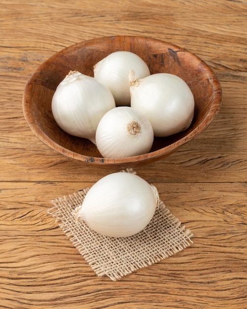 Oignons blancs dans un bol sur une table en bois