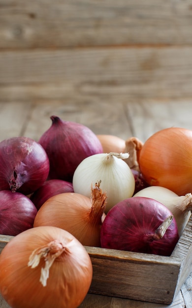 Photo oignons crus en boîte sur une table en bois