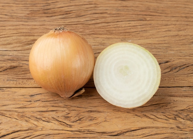 Oignons dorés et demi oignon sur table en bois