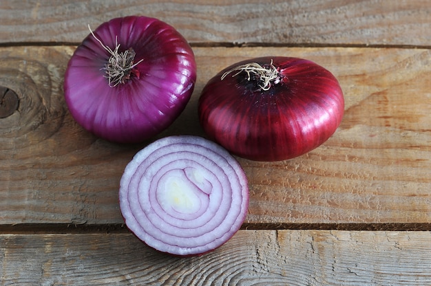 Oignons entiers et demi en rouge sur fond en bois rugueux