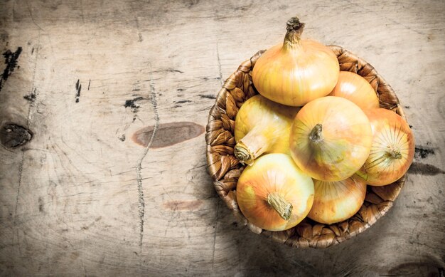 Oignons frais dans un panier. Sur un fond en bois.