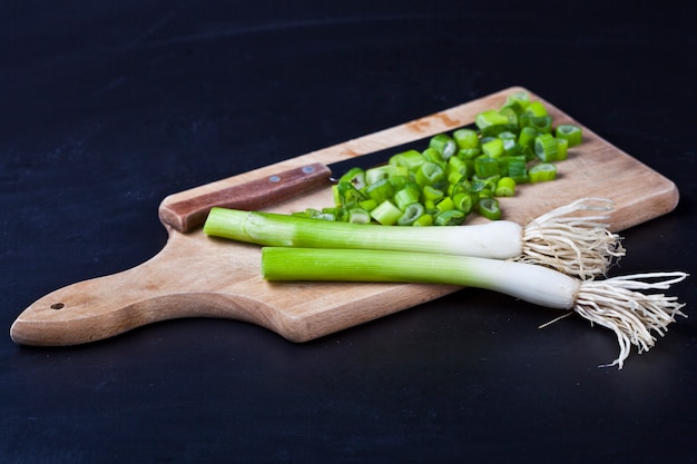 Oignons hachés biologiques frais et couteau sur une planche à découper