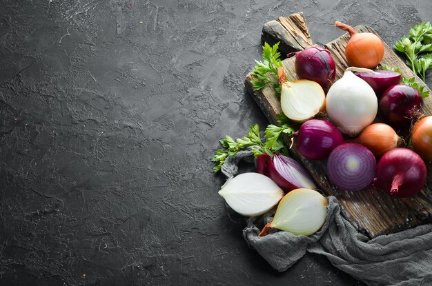 Oignons mûrs colorés sur planche de bois sur fond noir Vue de dessus Espace de copie gratuit