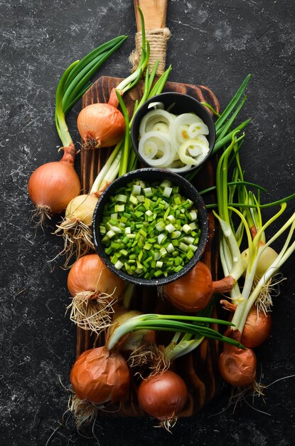 Oignons de printemps verts mûrs frais avec des oignons verts frais hachés sur fond de pierre noire Vue de dessus