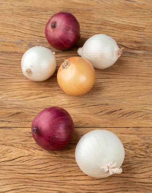 Oignons rouges blancs et dorés sur table en bois