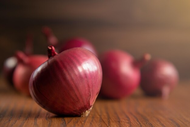 Oignons rouges sur bois rustique. Oignon violet frais sur fond de bois foncé. Espace de copie. Photographie d'atelier.