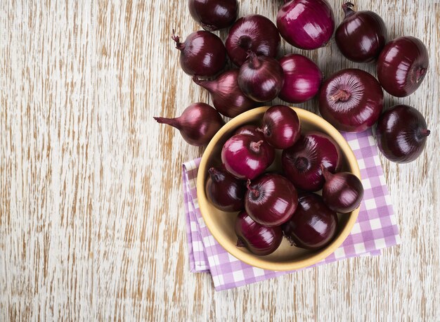 Oignons rouges dans un bol en bois sur bois