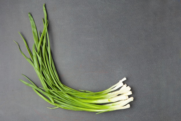 Oignons verts, sur un fond en bois noir. Oignons sur vieux bois. Oignon frais Oignon vert (concept alimentation et santé). Bouquet d'oignons verts frais