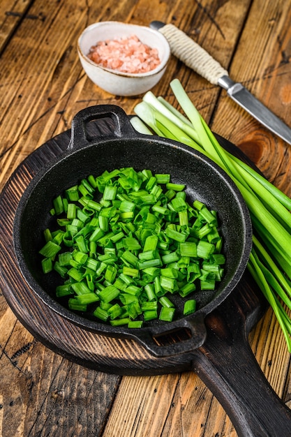 Oignons verts tranchés dans une casserole.