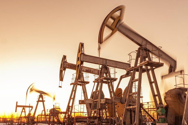 Oil Pumpjack contre un ciel coucher de soleil sur l'arrière-plan. équipement industriel. Machines à bascule pour la production d'électricité. Extraction d'huile. Guerre sur les prix du pétrole. Crise mondiale du coronavirus COVID 19.