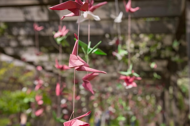 Oiseaux grues en origami accrochés aux fils dans le jardin en face des grues en papier colorées au soleil sur le