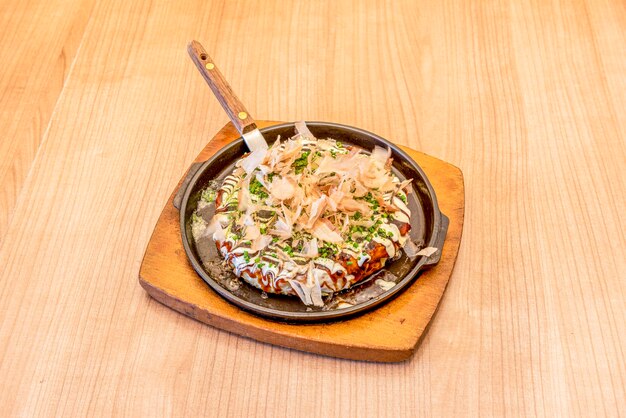 Photo okonomiyaki est un aliment japonais qui se compose d'une pâte avec des ingrédients cuits sur le gril le mot okonomiyaki est composé des honorifiques o konomi et yaki signifiant cuit à votre goût