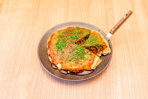 Photo okonomiyaki est un aliment japonais qui se compose d'une pâte avec des ingrédients cuits sur le gril le mot okonomiyaki est composé des honorifiques o konomi et yaki signifiant cuit à votre goût