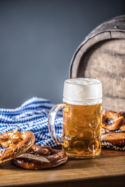 Photo oktoberfest grande bière avec un baril en bois de pretzel et une nappe bleue