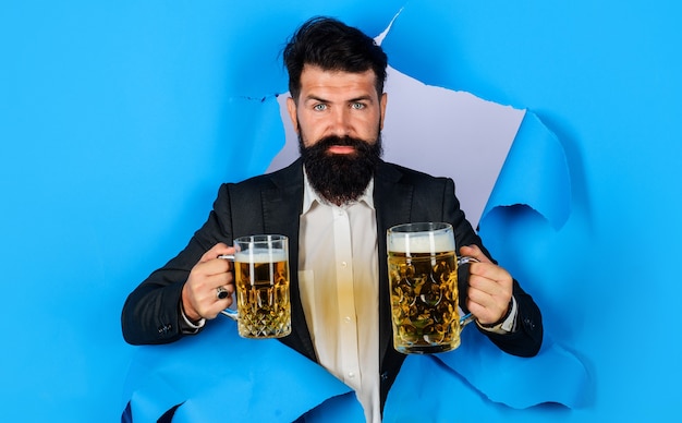 Oktoberfest. Homme barbu avec chope de bière regardant à travers le trou du papier. Concept de boissons, d'alcool et de personnes.