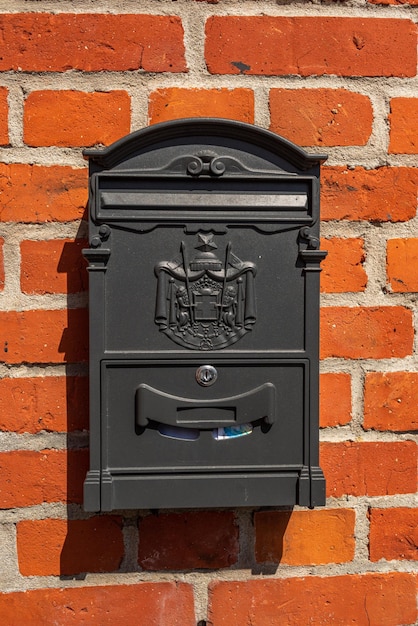 Old vintage post box noir sur un mur de briques rouges