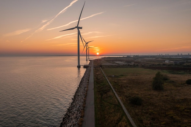 Éoliennes au coucher du soleil. Production d'énergie électrique écologique verte. Champ éco du parc éolien. Éolienne offshore et onshore ferme l'énergie verte en mer.