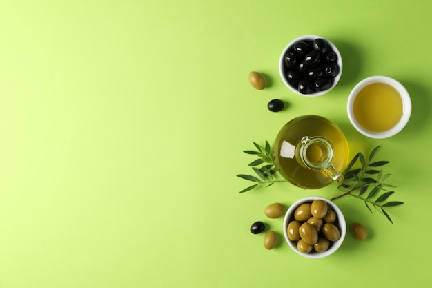 Olives, bouteille et bol d'huile d'olive sur vert, vue de dessus