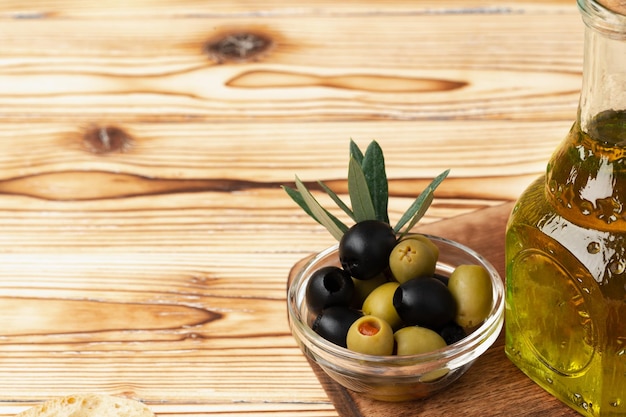 Olives et bouteille d'huile d'olive sur fond de bois