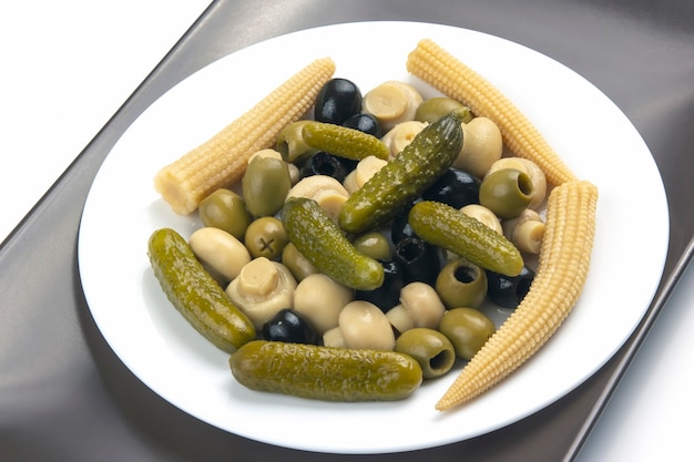 Olives, concombre mariné, champignons et maïs dans une salade sur une assiette.