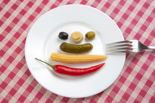 Olives, concombre mariné, piments rouges, champignons et maïs dans une salade sur une assiette