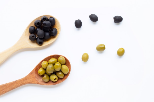 Olives sur une cuillère en bois, fond blanc.