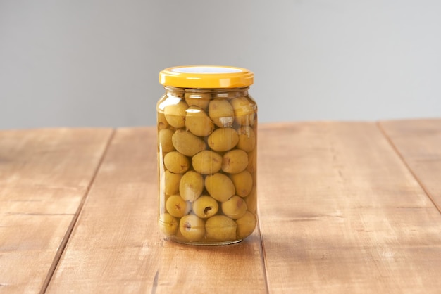 Olives dans un bocal en verre sur la table en bois.