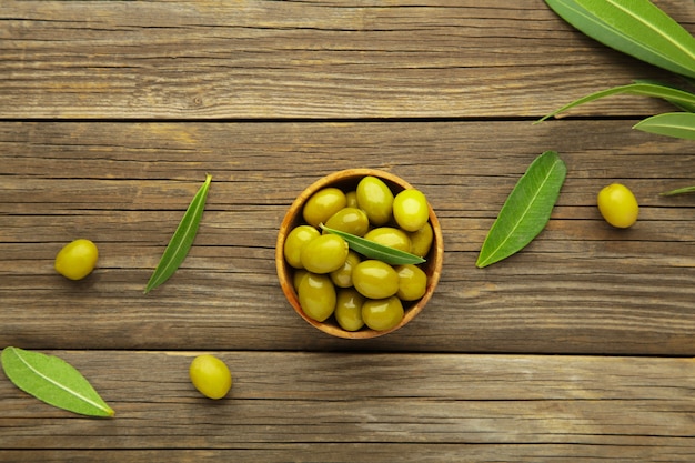 Olives fraîches dans un bol avec des feuilles sur fond gris avec espace de copie.