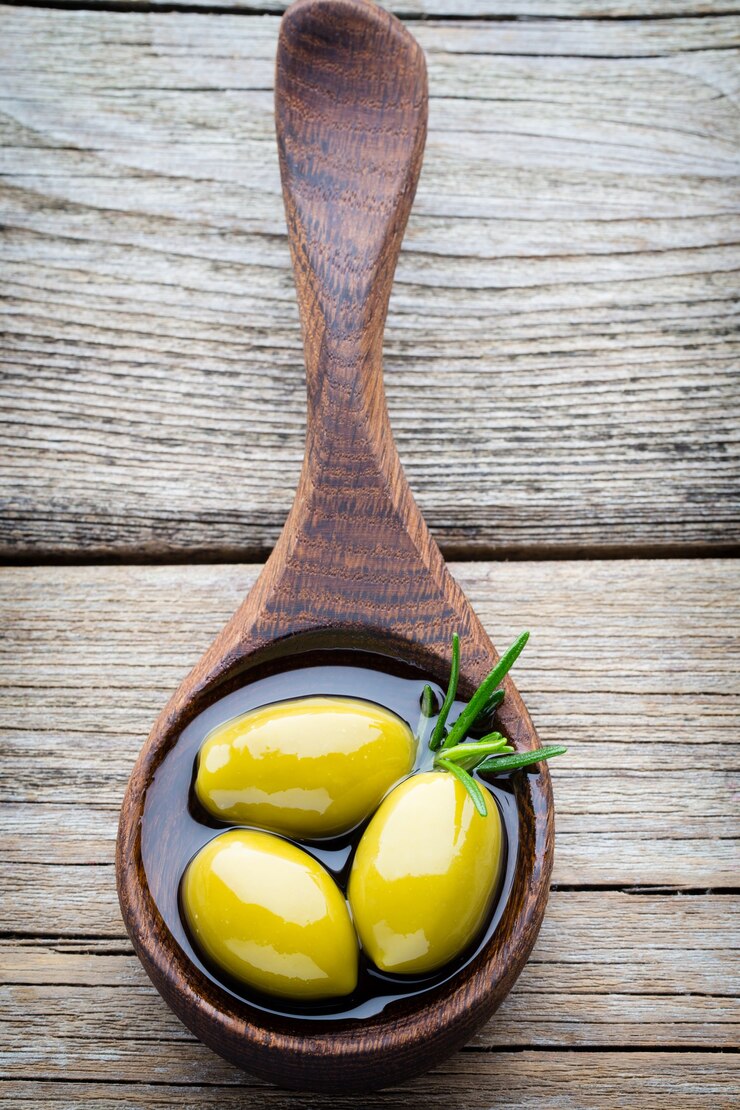 Photo olives fraîches et fond gris. olives dans un bol et cuillère.