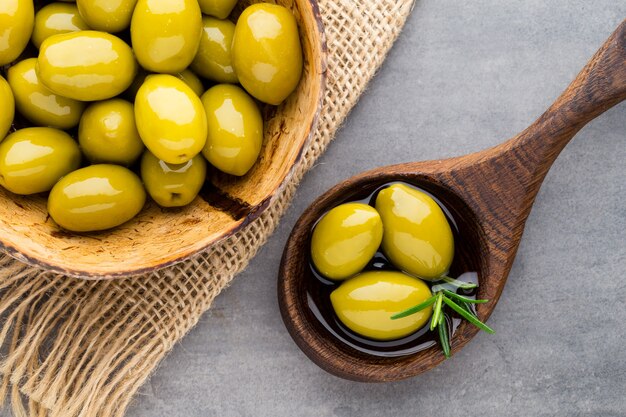 Olives fraîches et fond gris. Olives dans un bol et cuillère.