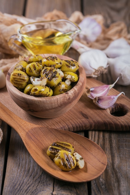 Olives grillées à l'ail, huile d'olive et épices sur fond de bois rustique