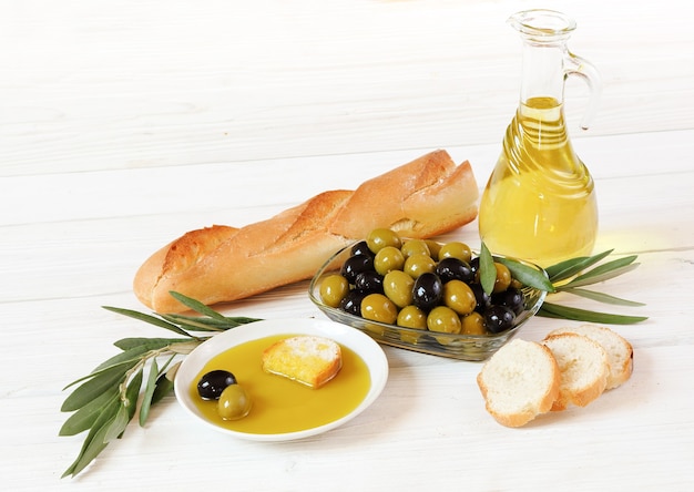 Photo olives, huile d'olive et pain, sur une table en bois blanche