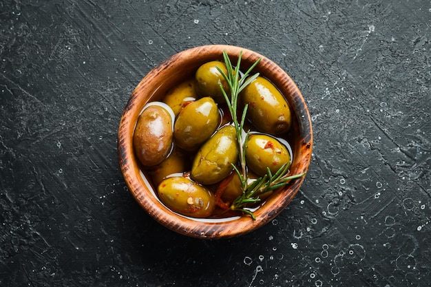 Olives marinées dans un bol en bois sur fond de pierre. Espace libre pour le texte.