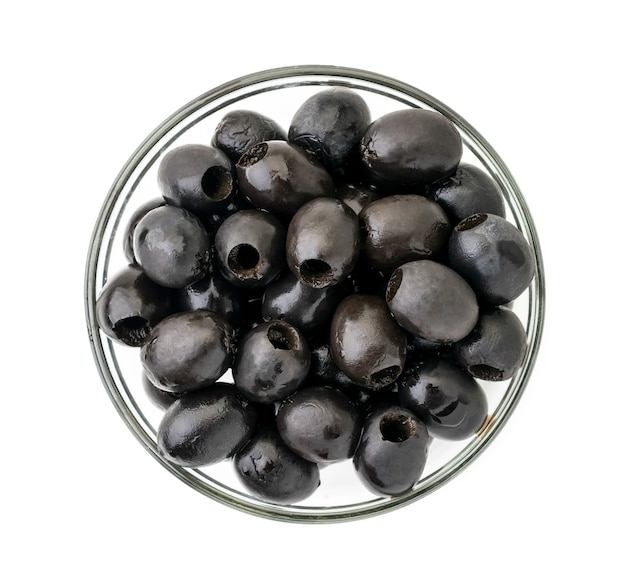 Olives noires dans une assiette en verre sur fond blanc. La vue du sommet.