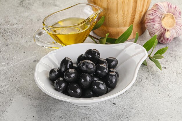 Olives noires dans le bol avec de l'huile et des branches