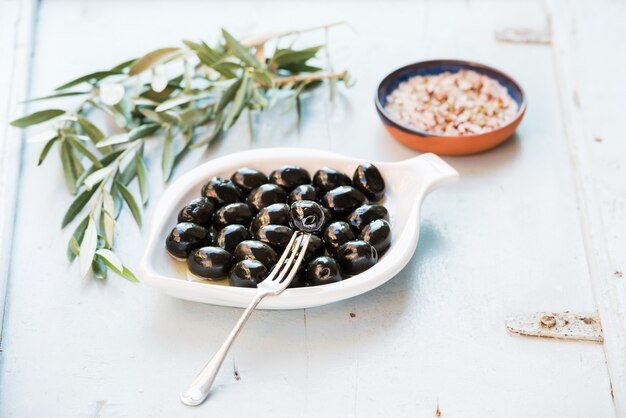 Olives Noires En Plaque De Céramique Blanche, Branches Et épices Sur Li