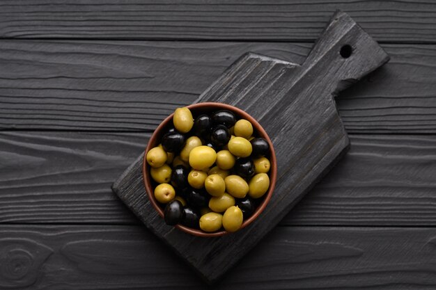 Olives noires et vertes sur un fond noir en bois foncé