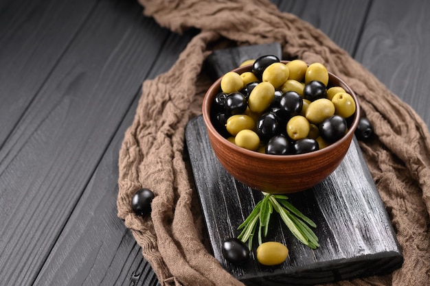 Olives noires et vertes sur un fond noir en bois foncé