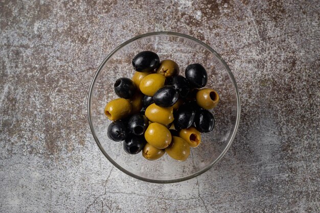 Olives et olives dans un verre sur fond de table en pierre grise