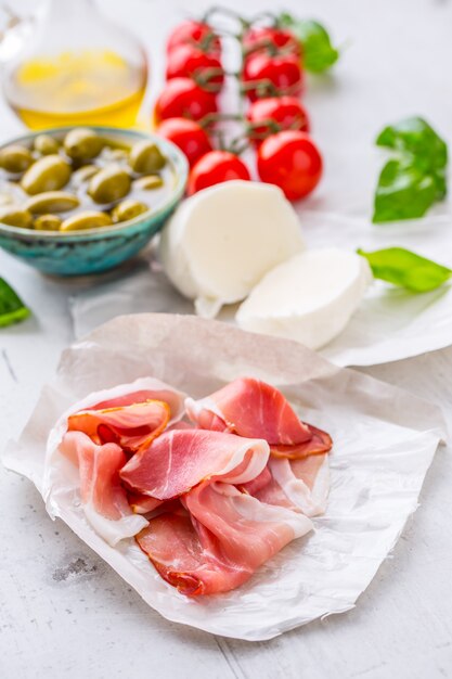 Photo olives prosciutto huile d'olive fromage mozzarella tomates ingrédients basilic cuisine italienne