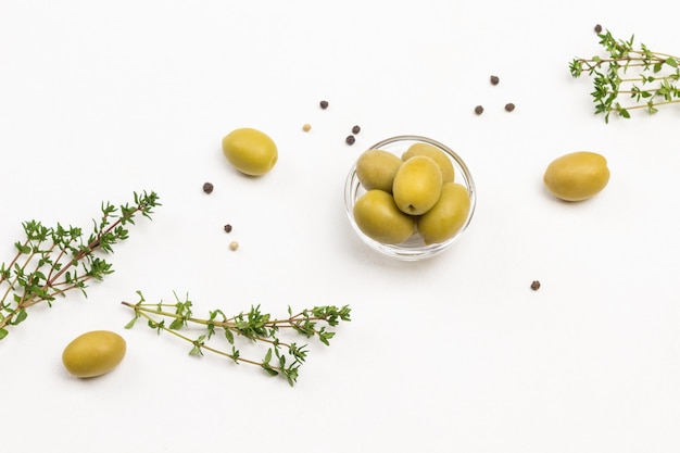 Olives vertes et brins de thym sur tableau blanc. Mise à plat.