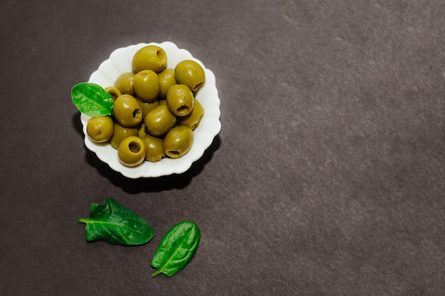 Olives vertes en conserve dans un bol blanc sur un tableau noir