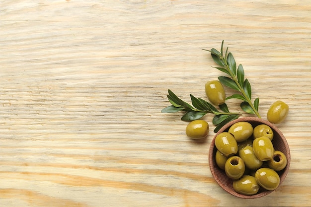 Olives vertes dans un bol avec des feuilles sur une table en bois naturel. vue de dessus. place pour le texte.