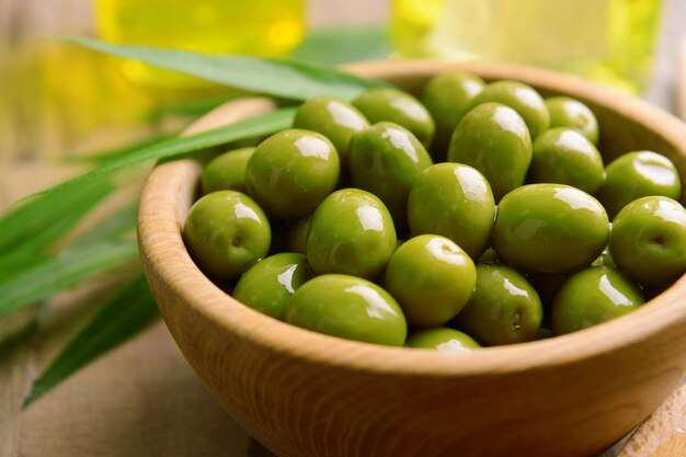 Olives vertes dans un bol avec des feuilles sur la table libre