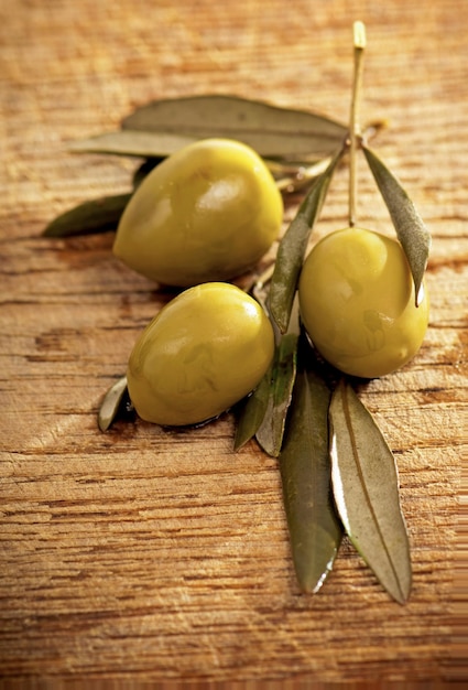 Olives vertes avec des feuilles sur la vue de dessus de fond en bois