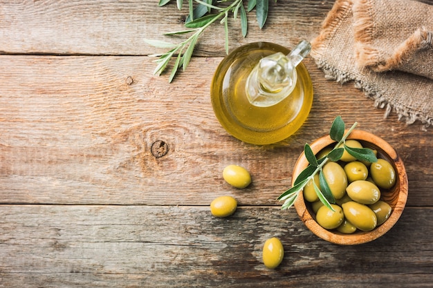 Photo olives vertes fraîches dans un bol et branche d'olivier sur bois rustique