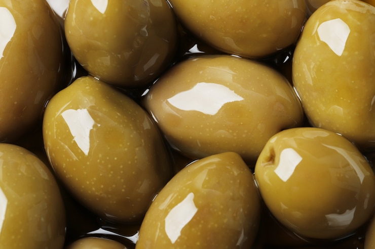 Photo olives vertes en gros plan d'huile comme toile de fond.
