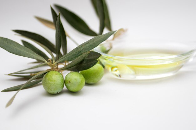 Olives vertes et huile d'olive sur fond blanc.