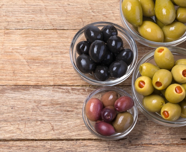 Photo les olives vertes et noires dans un bol sur fond de bois.